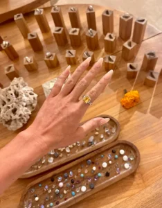 Hand wearing a custom-made silver ring with a yellow gemstone, displayed with various gem options during the best silver class in Bali.