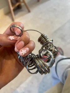 A person holding a ring size measuring set made of silver, often used in jewelry-making workshops like the best silver class in Bali.