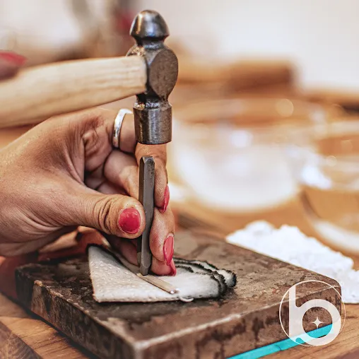 Close-up of a student crafting jewelry by hand using a hammer and stamping tool during the best silver class in Bali.